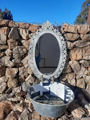 a mirror on a stone wall with a sink at Kwaggaskop Farm Stoephuis in Dullstroom