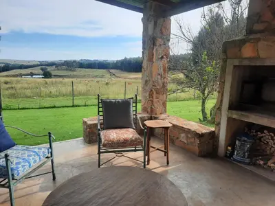 a porch with a chair and a table and a fireplace at Kwaggaskop Farm Stoephuis in Dullstroom
