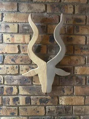 a wooden carving of a bird on a brick wall at Kudu's Rus in Marloth Park in Marloth Park