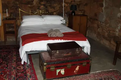 a bed with a pile of luggage sitting on it at Kwaggaskop Farm Kliphuis in Dullstroom