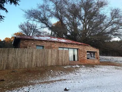 a brick house with a fence in front of it at Kwaggaskop Farm Kliphuis in Dullstroom