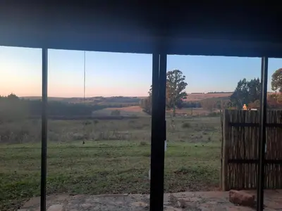 a view of a field from a window at Kwaggaskop Farm Kliphuis in Dullstroom