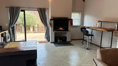 a living room with a fireplace and a table and a chair at Dullstroom Self Catering Blue Crane Estate 66 in Dullstroom