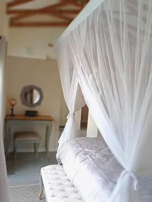 a bed with white curtains in a room with a table at Ndlovu Bushvilla at Elephant Rock Eco Estate in Mica
