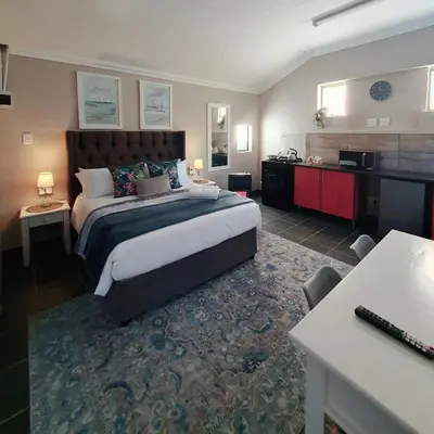 a large bedroom with a large bed and a desk at Tree Orchid in Polokwane