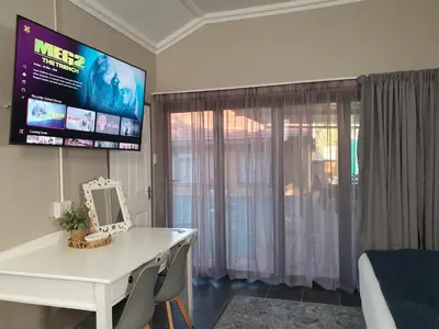 a white dressing table and mirror in a room at Tree Orchid in Polokwane