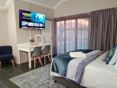 a bedroom with a bed and a desk and a television at Tree Orchid in Polokwane