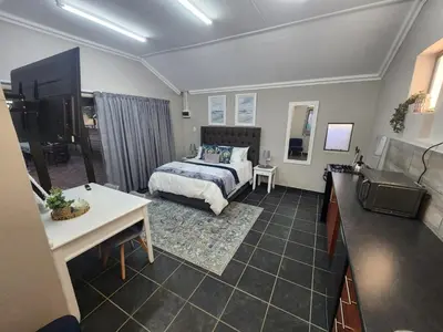 a bedroom with a bed and a desk and a television at Tree Orchid in Polokwane