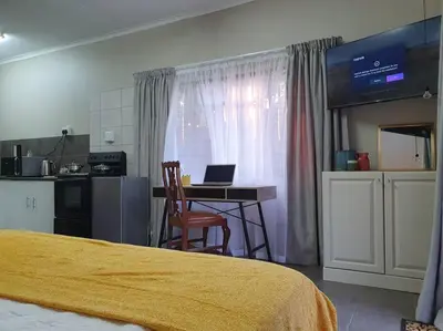 a bedroom with a bed and a table with a laptop at Tree Orchid in Polokwane