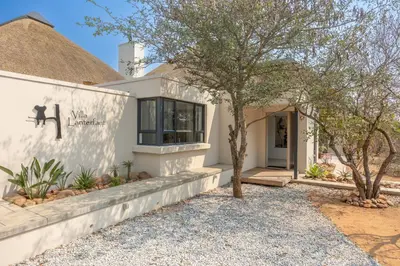 a white house with a tree in front of it at Villa Lanterfant - luxury stay in nature - solar powered in Hoedspruit
