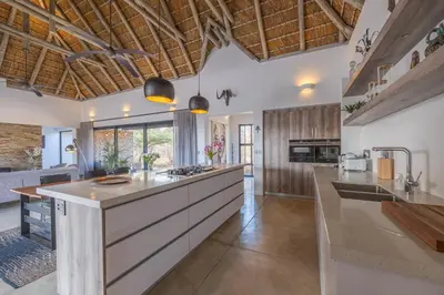 an open kitchen with wooden ceilings and a large island at Villa Lanterfant - luxury stay in nature - solar powered in Hoedspruit