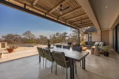 an open patio with a wooden table and chairs at Villa Lanterfant - luxury stay in nature - solar powered in Hoedspruit