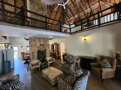 a living room filled with furniture and a fireplace at Bateleur Lodge, Mabalingwe in Bela-Bela