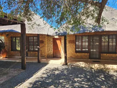 a brick house with a tree in front of it at Bateleur Lodge, Mabalingwe in Bela-Bela