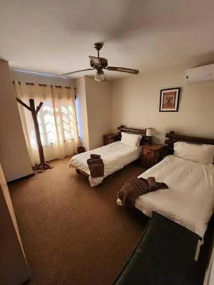 a bedroom with two beds and a ceiling fan at Bateleur Lodge, Mabalingwe in Bela-Bela