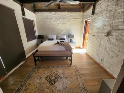 a bedroom with a bed and a stone wall at Boomhuis, Mabalingwe Nature Reserve in Bela-Bela