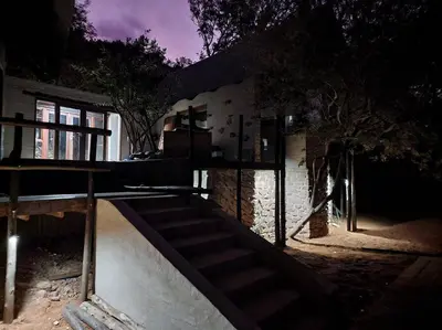 a house with a staircase in front of a building at Boomhuis, Mabalingwe Nature Reserve in Bela-Bela