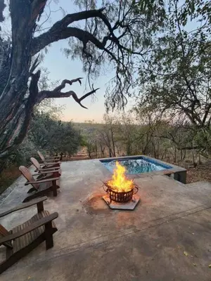 a fire pit with two benches and a pool at Boomhuis, Mabalingwe Nature Reserve in Bela-Bela