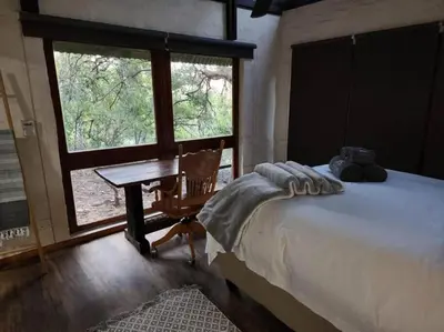 a bedroom with a bed and a desk and a window at Boomhuis, Mabalingwe Nature Reserve in Bela-Bela