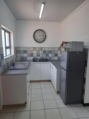 a kitchen with a black refrigerator and a clock on the wall at Partridge Place in Kempton Park
