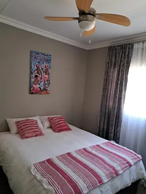 a bedroom with a bed with a ceiling fan at Partridge Place in Kempton Park