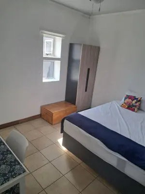 a bedroom with a bed and a table and a window at Partridge Place in Kempton Park