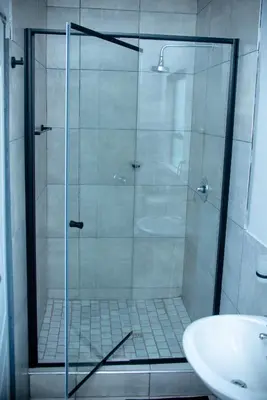a shower with a glass door next to a sink at Lugogo Guesthouse in Thohoyandou