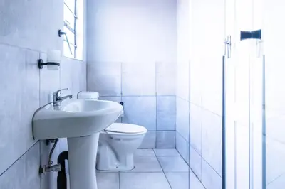 a white bathroom with a toilet and a sink at Lugogo Guesthouse in Thohoyandou