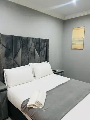 a bedroom with a large white bed with a headboard at Lugogo Guesthouse in Thohoyandou