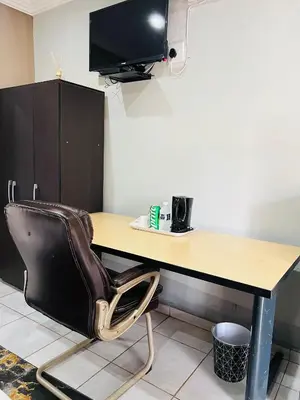 a chair sitting in front of a desk with a television at Lugogo Guesthouse in Thohoyandou