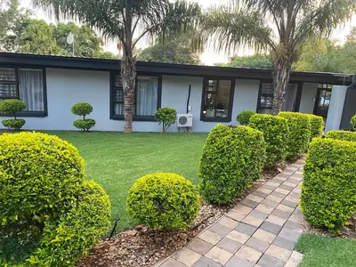 a house with bushes in front of a yard at Bridgelamour Accommodation in Hartbeespoort