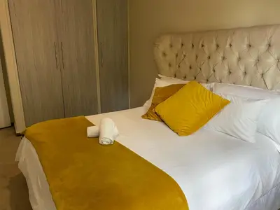 a bed with yellow and white pillows and a yellow blanket at Bridgelamour Guest House in Hartbeespoort