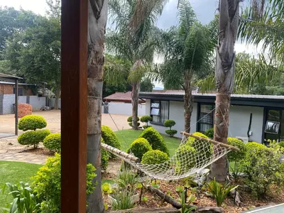 a hammock in a garden in front of a house at Bridgelamour Guest House in Hartbeespoort