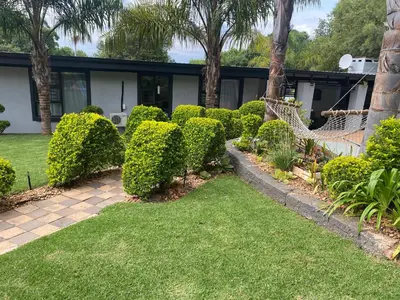 a garden with bushes and a house at Bridgelamour Guest House in Hartbeespoort