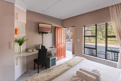 a bedroom with a bed and a desk with a computer at Villa Africa Boutique Hotel & Spa in Pretoria