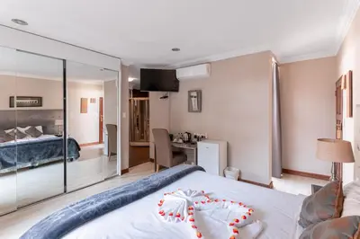 a bedroom with a large white bed with a glass wall at Villa Africa Boutique Hotel & Spa in Pretoria