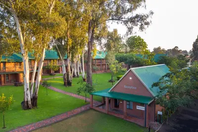 a building with a green roof in a park with trees at Bluegum Country Lodge in Bethal