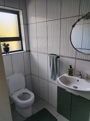a bathroom with a toilet and a sink and a window at Waterfront Guest House in Hartbeespoort