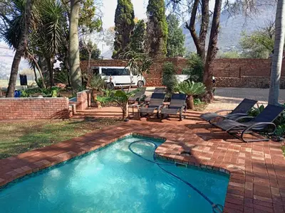a swimming pool with two chairs at Waterfront Guest House in Hartbeespoort