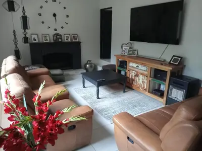 a living room with couches and a flat screen tv at Waterfront Guest House in Hartbeespoort