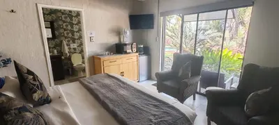 a bedroom with a bed and a chair and a window at Waterfront Guest House in Hartbeespoort
