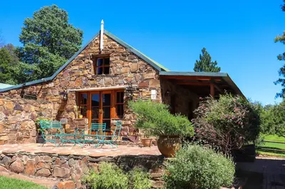 a stone house with blue chairs in front of it at Strathwold Cottages in Machadodorp