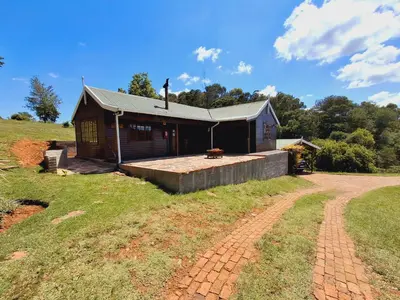 a house on a hill with a dirt road in front of it at Strathwold Cottages in Machadodorp