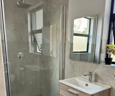 a bathroom with a shower and a sink and a mirror at Sango on 9 in Naboomspruit