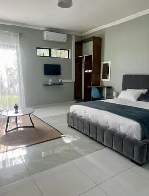 a bedroom with a large bed and a table at Sango on 9 in Naboomspruit