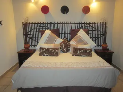 a bed with brown and white pillows on it at Mon Repos Guest Farm in Bela-Bela