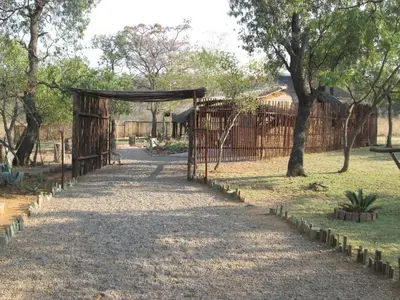 a path in a park with a gate and trees at Mon Repos Guest Farm in Bela-Bela