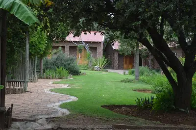 a garden with a brick house and a walkway at Mon Repos Guest Farm in Bela-Bela