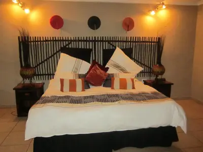 a bedroom with a large bed with a black headboard at Mon Repos Guest Farm in Bela-Bela
