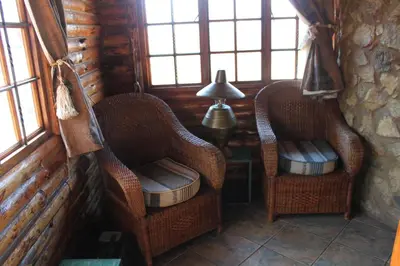 two wicker chairs sitting in a room with windows at Adansonia Eco Lodge in Musina
